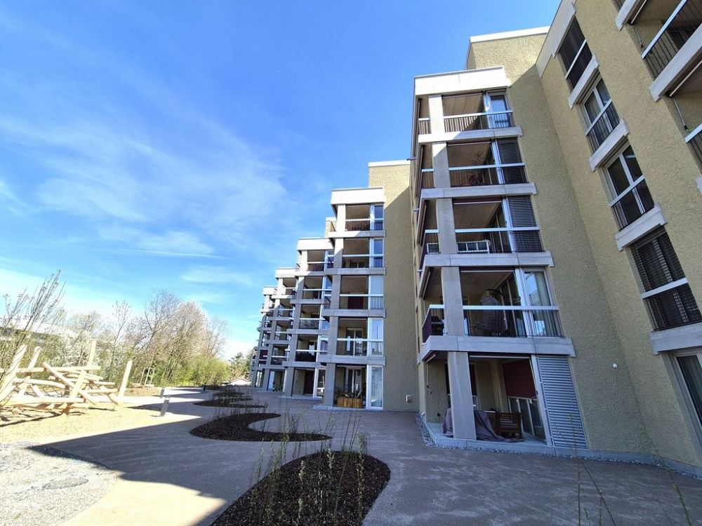 Attraktive und charmante Neubauwohnung mit Sitzplatz an bester Lage - Hausansicht Hinterseite